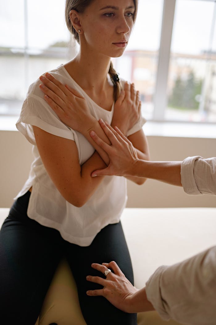 Woman in white shirt receiving therapeutic care in a clinic setting.